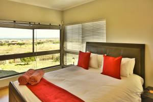 a bedroom with a bed with red pillows and a window at Bayview 8 Sleeper Langebaan in Langebaan