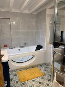 La salle de bains est pourvue d'une baignoire avec un tapis jaune. dans l'établissement Le cocon sauternais avec balneo, à Preignac
