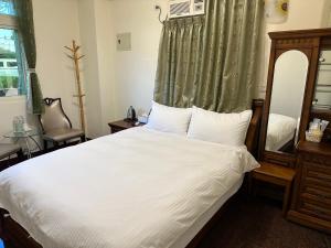 花蓮市にある偕安民宿のベッドルーム(鏡付きの大きな白いベッド1台付)