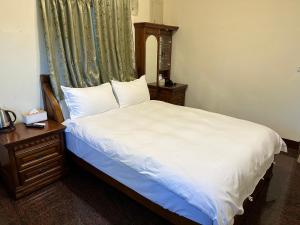 花蓮市にある偕安民宿のベッドルーム1室(白いベッド1台、ドレッサー、窓付)