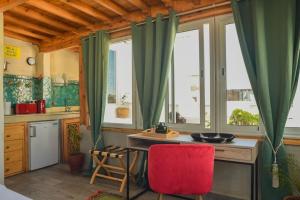 a kitchen with green curtains and a red chair at Stella 4 - studio deluxe, rooftop en médina in Essaouira