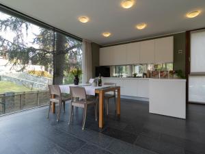 una cucina con tavolo e sedie e una grande finestra di Mamma Ciccia - ecofriendly villa on Lake Como a Malgrate