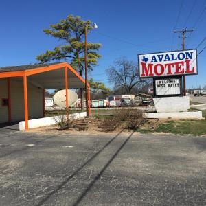 una señal de motel frente a una gasolinera en Avalon Motel, en Early