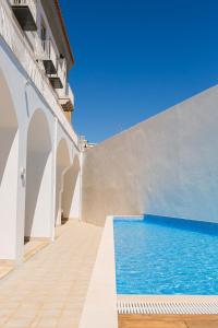 a house with a swimming pool and a white wall at Querido Algarve Apartment in Faro