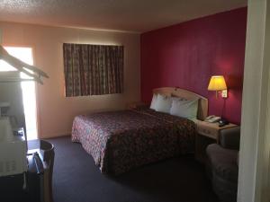 ein Hotelzimmer mit einem Bett und einer roten Wand in der Unterkunft Avalon Motel in Early