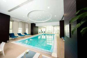 a swimming pool in a hotel room with blue chairs at Ramada Encore Doha by Wyndham in Doha