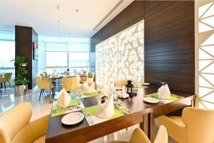 a dining room with a table and yellow chairs at Ramada Encore Doha by Wyndham in Doha