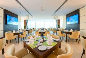 a restaurant with tables and chairs in a room at Ramada Encore Doha by Wyndham in Doha