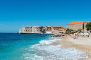 vistas a una playa con un castillo en el fondo en Sunlit Comfort Apartments, en Dubrovnik