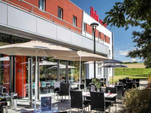 un restaurante con mesas y sombrillas frente a un edificio en Ibis Saint-Genis-Pouilly Genève en Saint-Genis-Pouilly