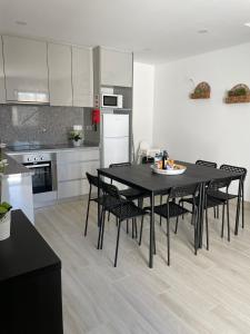 eine Küche mit einem schwarzen Tisch und schwarzen Stühlen in der Unterkunft Porto Smart Apartments Comfort in Perafita