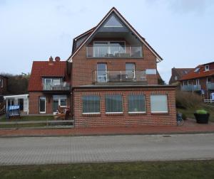 uma casa de tijolos vermelhos com uma varanda numa rua em Haus ohne Namen Juist em Juist