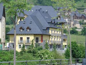 duży żółty dom z czarnym dachem w obiekcie Hotel Spa Acevi Val d’Aran w mieście Vielha