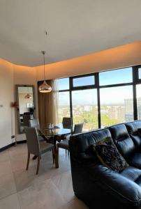 a living room with a black leather couch and a table at City View Apartment Nestled in the Heart of NBO in Nairobi