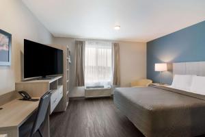 a hotel room with a bed and a flat screen tv at WoodSpring Suites Morrisville - Raleigh Durham Airport in Morrisville
