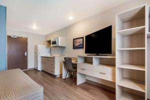 a small room with a desk and a tv and a room with a bed at WoodSpring Suites Morrisville - Raleigh Durham Airport in Morrisville