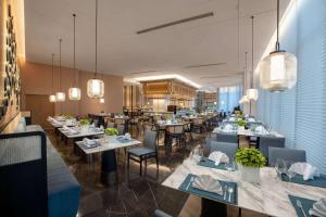 um restaurante com muitas mesas, cadeiras e luzes em Wyndham Xiong'an em Baoding