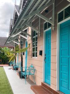 um alpendre com portas azuis e bancos numa casa em Gading Chalet em Kuala Terengganu