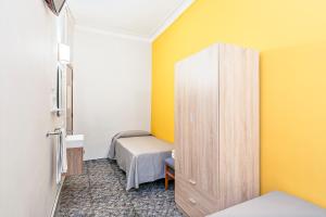 Habitación pequeña con cama y pared amarilla en Hostal Santa Ana, en Barcelona