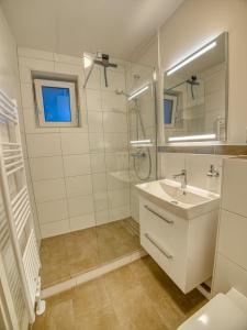 a white bathroom with a sink and a mirror at Meer mit Blick, Dat witte Hus in Rettin