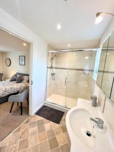ein Bad mit einem Waschbecken, einer Dusche und einem Bett in der Unterkunft Webbys Windrush Walk in Bourton on the Water