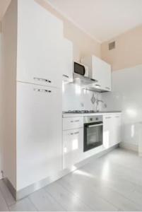 a white kitchen with white cabinets and a stove at Casa Davide in Sottomarina