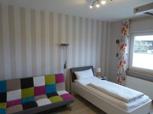 a bedroom with a bed and a couch and a window at Gästehaus Steker in Bad Driburg