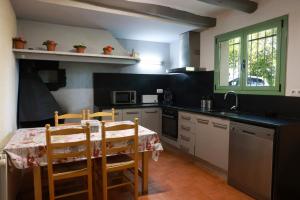 cocina con mesa con sillas y fregadero en Masia Rural Cal Belles Mas, en Riudarenes
