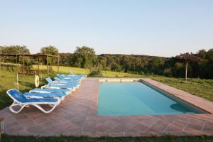 una fila di sedie a sdraio accanto alla piscina di Masia Rural Cal Belles Mas a Riudarenes