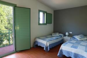 1 dormitorio con 2 camas y balcón en Masia Rural Cal Belles Mas, en Riudarenes