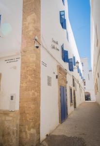 a narrow alley with a building with blue shutters at Stella 1 - joli appartement en médina avec cheminée in Essaouira