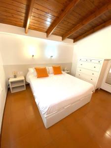 a white bed with two orange pillows in a room at Private Apartments Cala Canyelles in Lloret de Mar