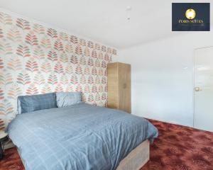a bedroom with a bed with a blue comforter at Fobis Suites Short Lets for 3 Bed Family Group Contractors Dagenham in Dagenham