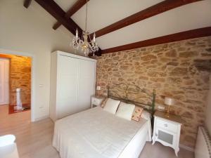 1 dormitorio con cama y pared de piedra en Casa Xan, en Jove (Xove)