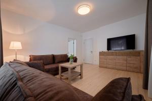 ein Wohnzimmer mit einem Sofa und einem TV in der Unterkunft Jonavos alpakų svečių namai in Jonava
