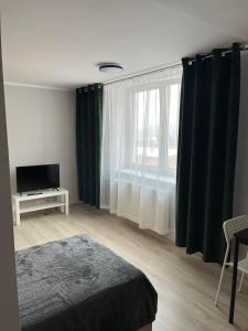 1 dormitorio con 1 cama, TV y ventana en Pokoje na Górce, en Rajgród