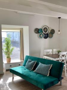 un sofá verde en una sala de estar con ventana en Alojamento confortável a 2 min da Praia en Horta