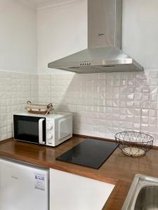 a kitchen with a white microwave and a sink at Alojamento confortável a 2 min da Praia in Horta