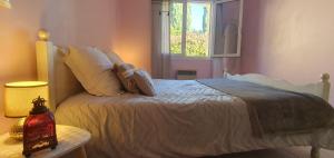 a bedroom with a white bed with a window at Petite maison au calme garrigue et mer Montpellier in Teyran