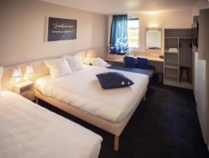una camera d'albergo con 2 letti e una scrivania di Ace Hotel Issoire a Issoire