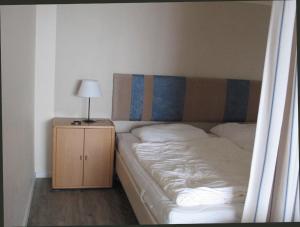 ハイリゲンハーフェンにあるIhr Meehrblickのベッドルーム1室(ベッド1台、ナイトスタンド、ランプ付)