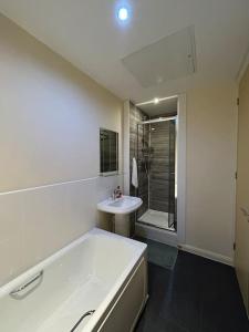 La salle de bains blanche est pourvue d'une baignoire et d'un lavabo. dans l'établissement Comfortable 3-Storey House with Free Car Parking, à Manchester
