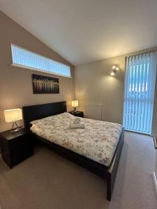 Comfortable 3-Storey House with Free Car Parking في مانشستر: غرفة نوم بسرير مع مصباحين ونوافذ اثنين
