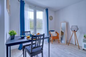 uma sala de jantar com uma mesa e cadeiras azuis e uma janela em LOGEMENT AARON em Courcouronnes