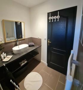 a bathroom with a black door and a sink at Le Repaire du Soleil in Aigues-Mortes