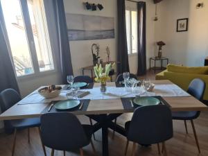 a dining room with a table with chairs and a couch at Le Repaire du Soleil in Aigues-Mortes
