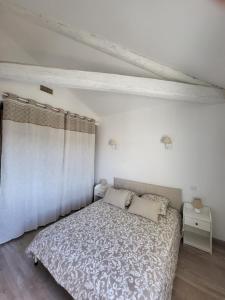 a white bedroom with a bed and a curtain at Le Repaire du Soleil in Aigues-Mortes