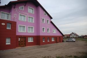 a pink and purple building with a car parked in front at Noclegi"DOM RÓŻANY" Myszyniec in Myszyniec