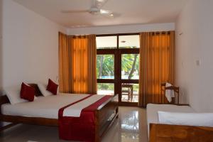 a bedroom with two beds and a large window at High Park Hotel in Nilaveli