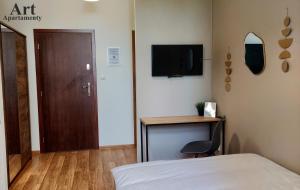- une chambre avec un lit, un bureau et une télévision dans l'établissement Art Apartamenty 1, à Kalisz